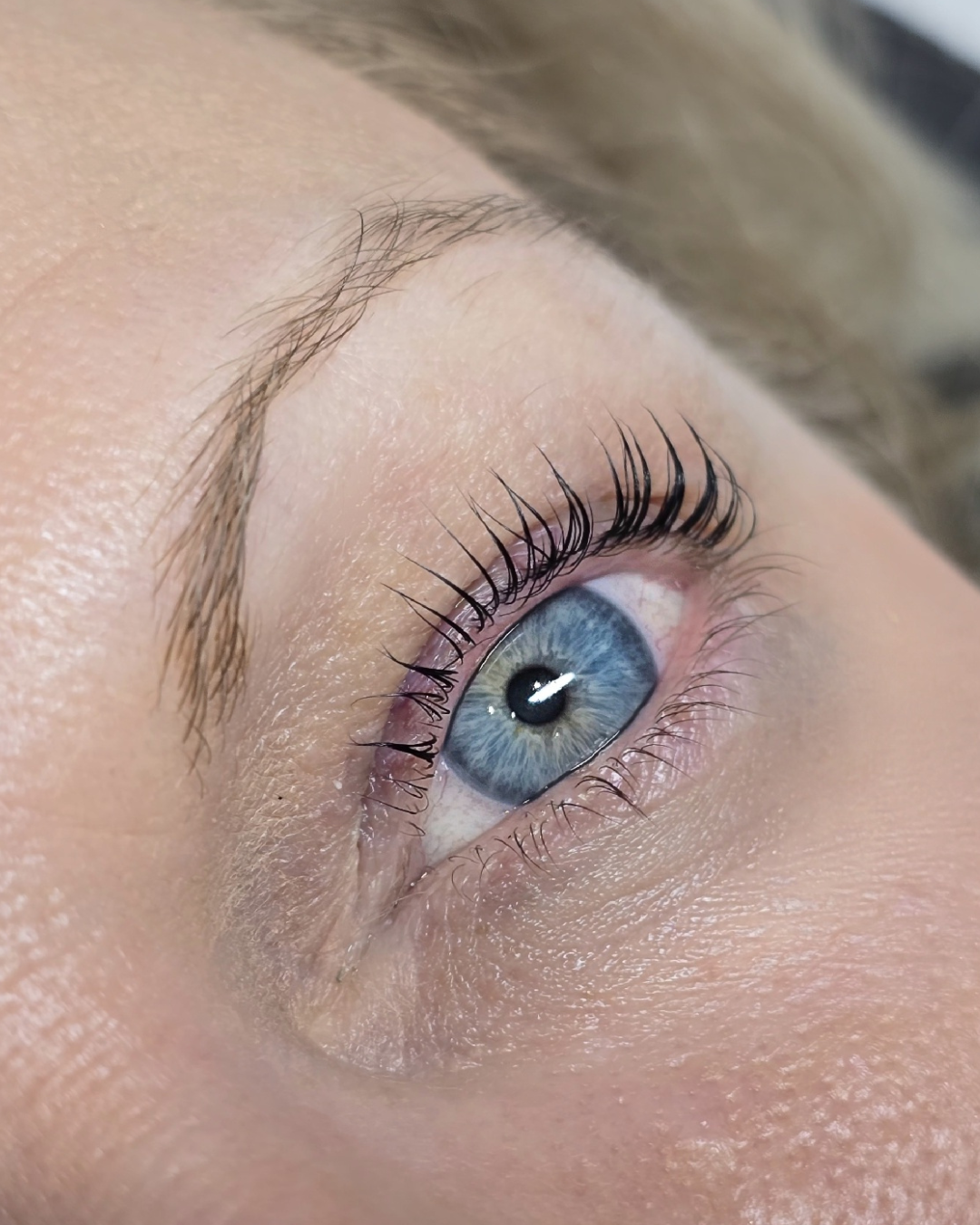 Lash lift result on blue-eyed client with lifted, separated lashes and natural brows